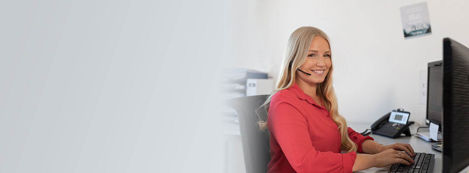 Frau mit Headset am Computer sitzend
