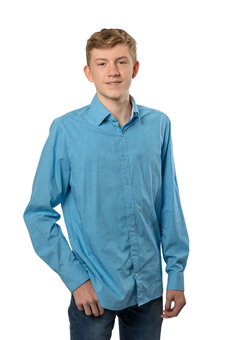 Person in hellblauem, langärmligem Hemd steht halbfrontal, eine Hand in der Hosentasche. Leichte Kopfneigung und neutrales Lächeln. Studio-Porträt vor weißem Hintergrund, Jeans sichtbar, keine weiteren Elemente.