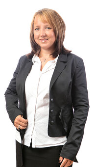 Person in schwarzem Blazer und weißer Bluse steht frontal, blickt zur Kamera und hält mit der rechten Hand den Blazer; neutraler weißer Hintergrund, Oberkörper bis Hüfte sichtbar.